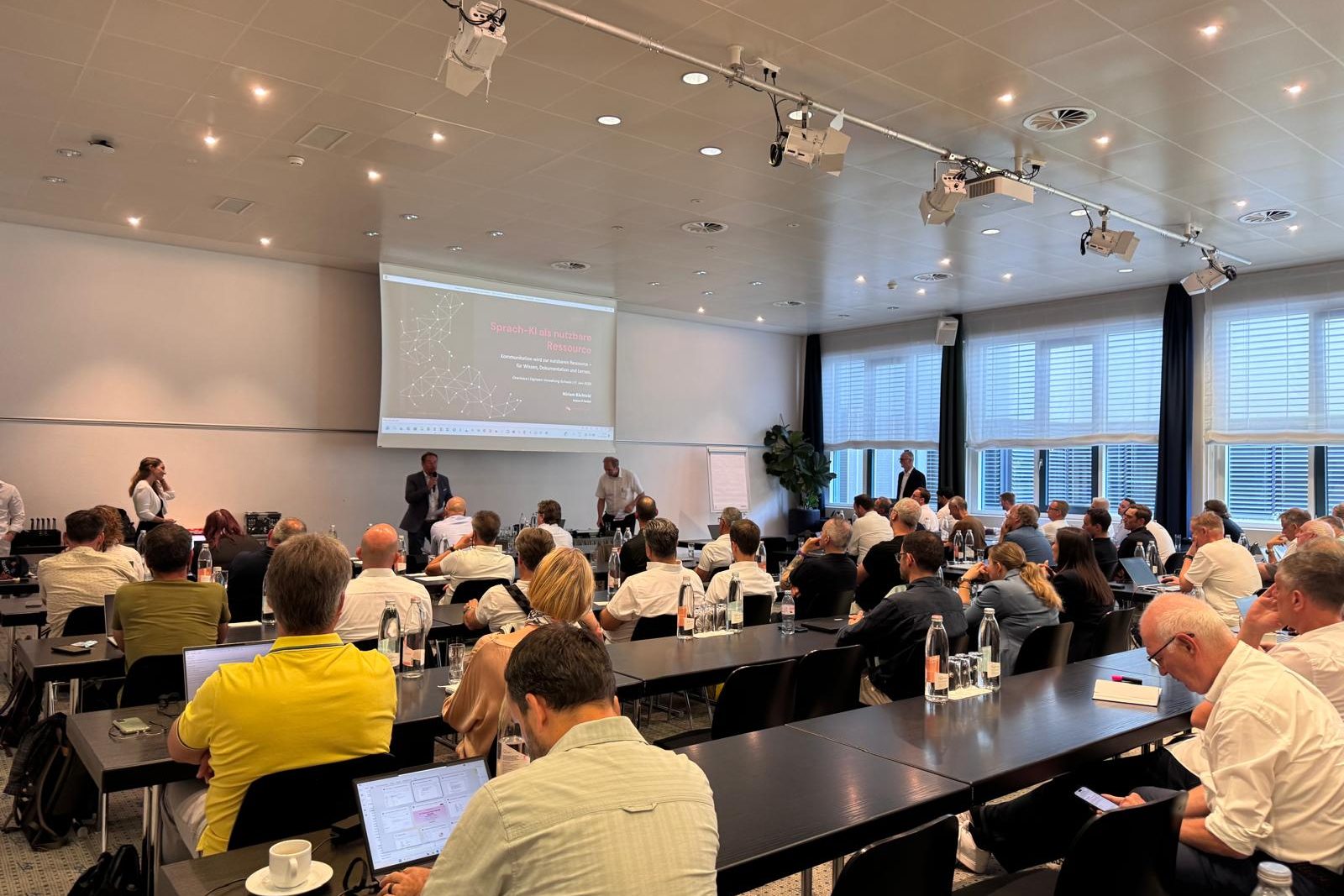 Salle comble lors de l'événement OneVoice de l'Administration numérique suisse, avec la diapositive de titre sur l'IA vocale